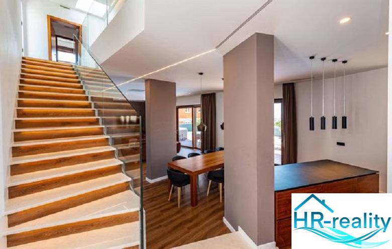 Innenraum der Villa mit Holzboden, Treppe und Esstisch.