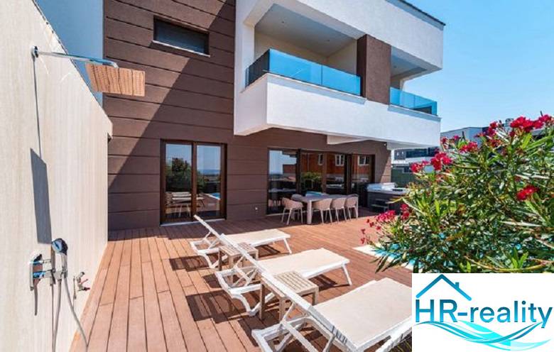 Terrasse mit Liegestühlen bei der Villa in Novalja mit Meerblick und Dusche.