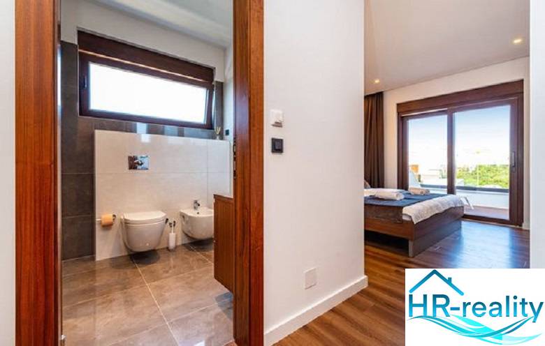 Innenraum der Villa mit Holzboden, Schlafzimmer und Badezimmer mit großem Fenster.