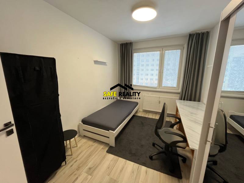 Schlafzimmer in einer 3-Zimmer-Wohnung mit Bett, Tisch und Holzboden.