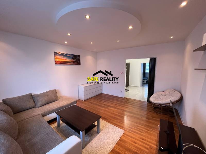 Wohnzimmer in einer 3-Zimmer-Wohnung mit einem bequemen Sofa und einem Boden in Holzoptik.