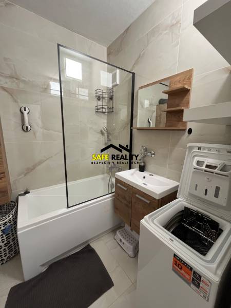 Badezimmer mit Badewanne, Schrank und Waschmaschine in einer 3-Zimmer-Wohnung.