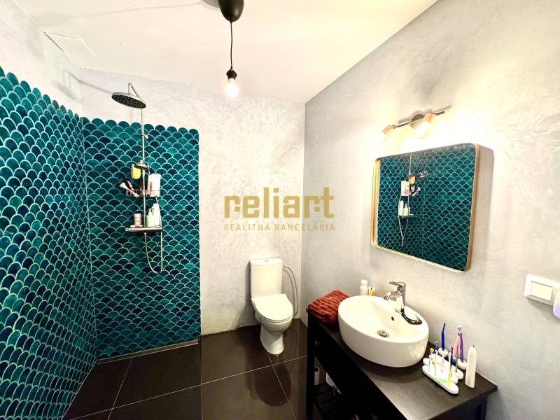 Badezimmer mit dunklem Boden und blauen Fliesen in einem Einfamilienhaus.