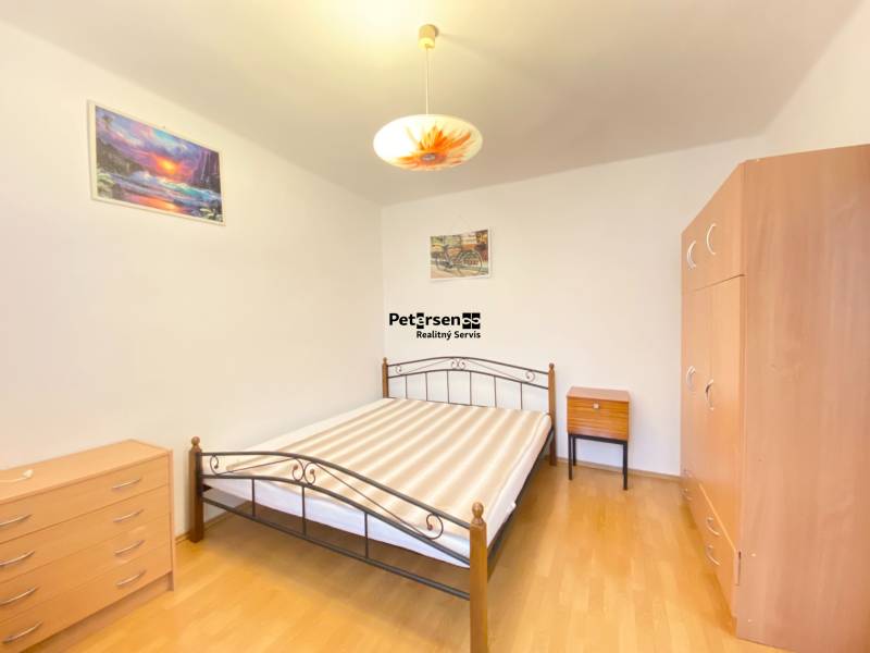 Schlafzimmer in einer 2-Zimmer-Wohnung mit Bett, Schrank und Boden in Holzoptik.