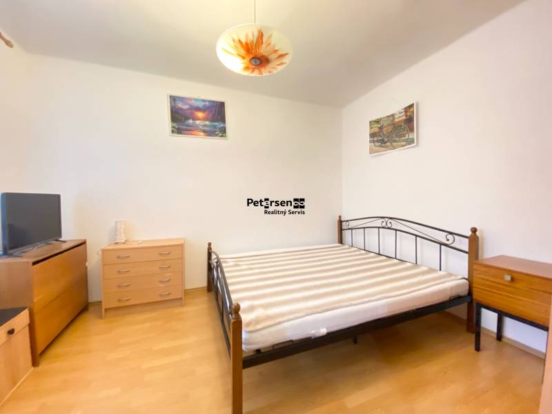 Schlafzimmer in einer 2-Zimmer-Wohnung mit Möbeln und Boden in Holzoptik.