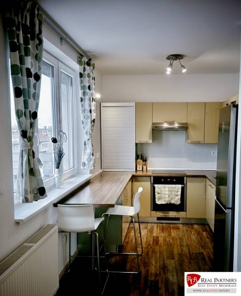 Küche in einer 3-Zimmer-Wohnung mit Bartresen, Holzboden und großem Fenster.