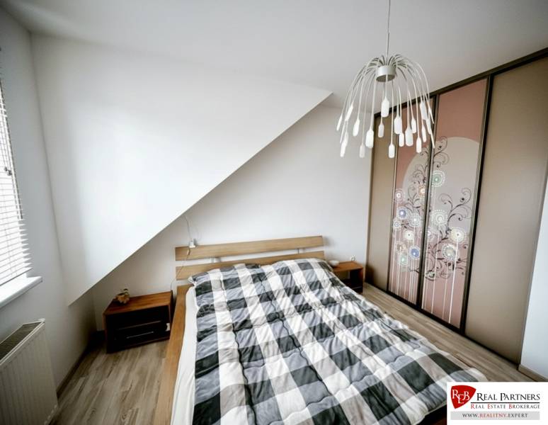 Schlafzimmer in einer 3-Zimmer-Wohnung mit Bett, Einbauschrank und Boden mit Holzdekor.