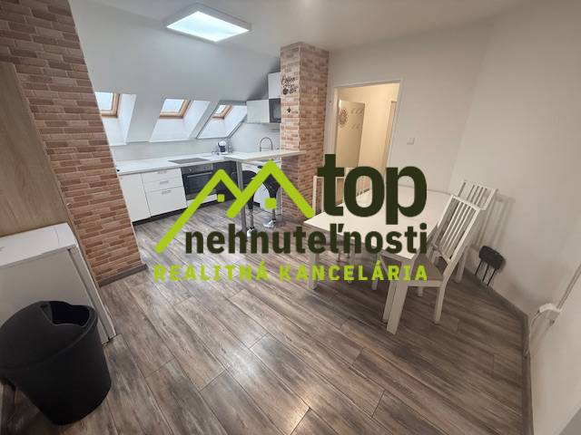 Innenraum einer Einzimmerwohnung mit Holzboden und einer Küche mit Ziegelverkleidung.