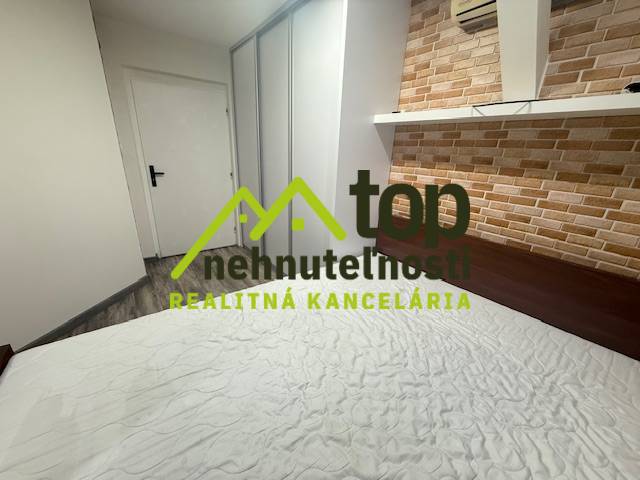 Schlafzimmer mit Ziegeldekor in einer Einzimmerwohnung, auf dem Boden ein Bodenbelag mit Holzdekor.