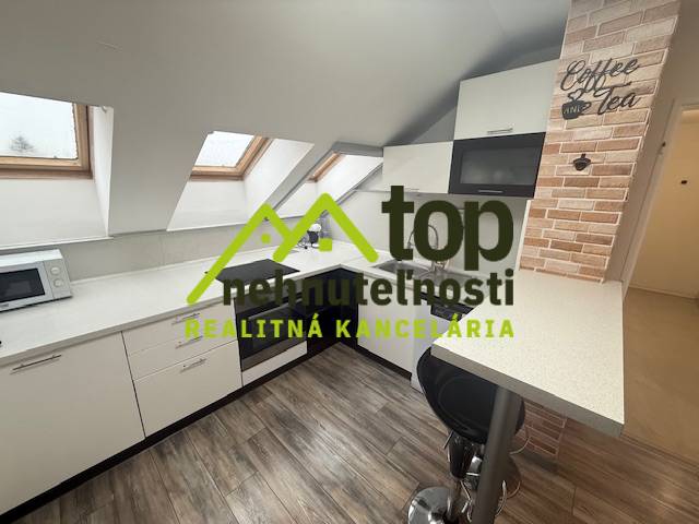 Küchenbereich in einer Einzimmerwohnung mit Holzboden und Dachfenstern.