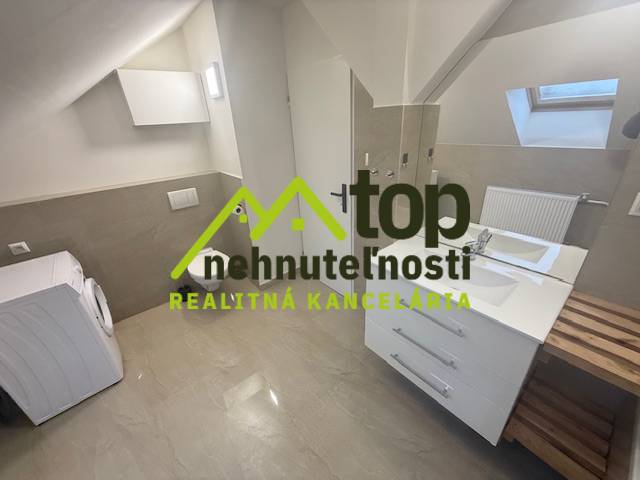 Badezimmer im Dachgeschoss einer Einzimmerwohnung mit Waschmaschine und Waschbecken, Boden mit Holzdekor.