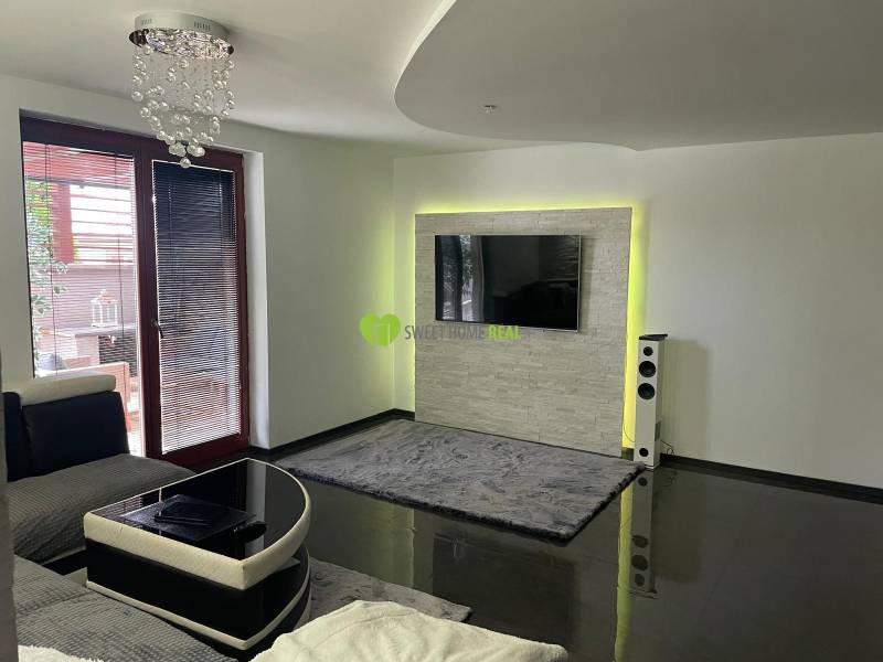 Wohnzimmer in einem Einfamilienhaus mit glänzendem Boden und Fernseher an der Wand.