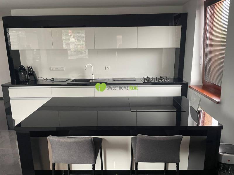 Küche in einem Einfamilienhaus mit glänzenden schwarz-weißen Möbeln und einer Essbar.