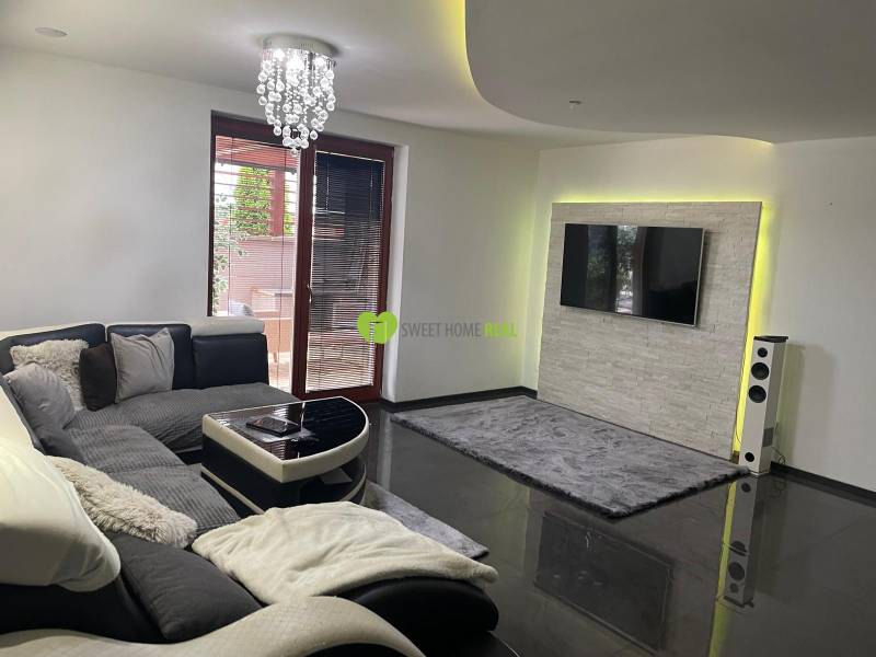 Wohnzimmer in einem Einfamilienhaus mit Sofa und Fernseher an der Wand mit Steinverkleidung.