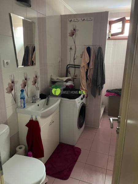 Badezimmer im Einfamilienhaus mit Sanitäranlagen, Waschmaschine und Blumenfliesen.