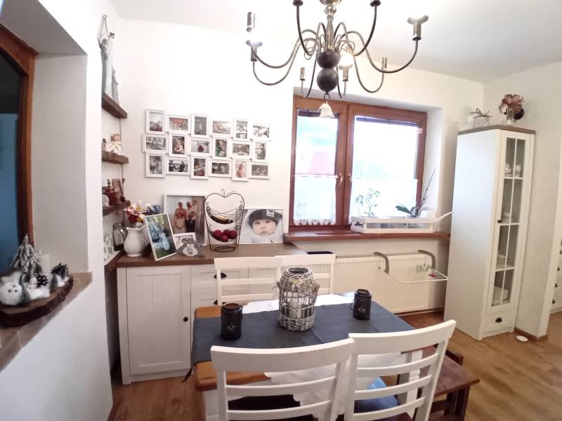 Esszimmer in einem Einfamilienhaus mit weißen Möbeln, Bildern an der Wand und einem dekorativen Kronleuchter.