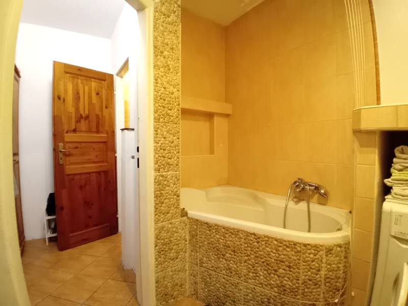 Ein Badezimmer in einem Einfamilienhaus mit einer mit Steinverkleidung ummantelten Badewanne und Holztüren.