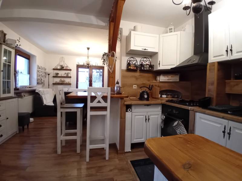 Küche und Wohnzimmer in einem Einfamilienhaus mit Holzboden und weißen Möbeln.