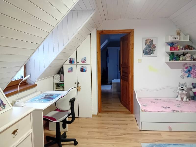 Kinderzimmer in einem Einfamilienhaus mit Schreibtisch und Bett, Boden mit Holzdekor.
