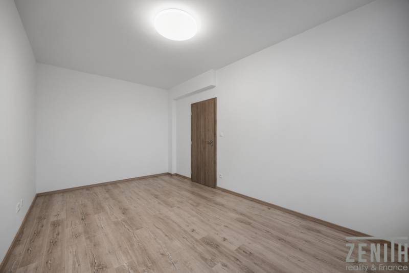 Ein leerer Raum mit Holzboden in einer Zweizimmerwohnung.