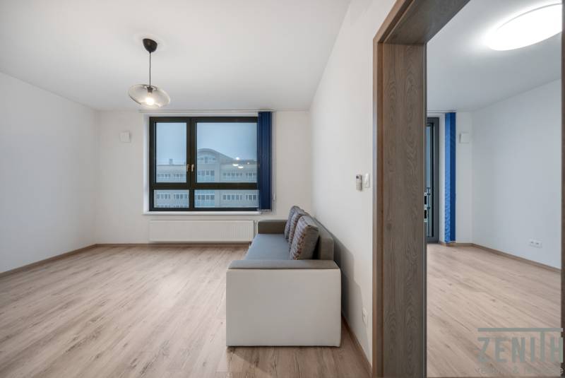 Wohnzimmer mit Sofa, großem Fenster und Holzboden in einer 2-Zimmer-Wohnung.