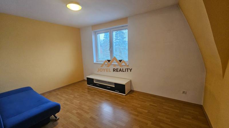 Ein Zimmer mit einem blauen Sofa, einem Boden in Holzoptik und weißen Möbeln in einer 3-Zimmer-Wohnung.