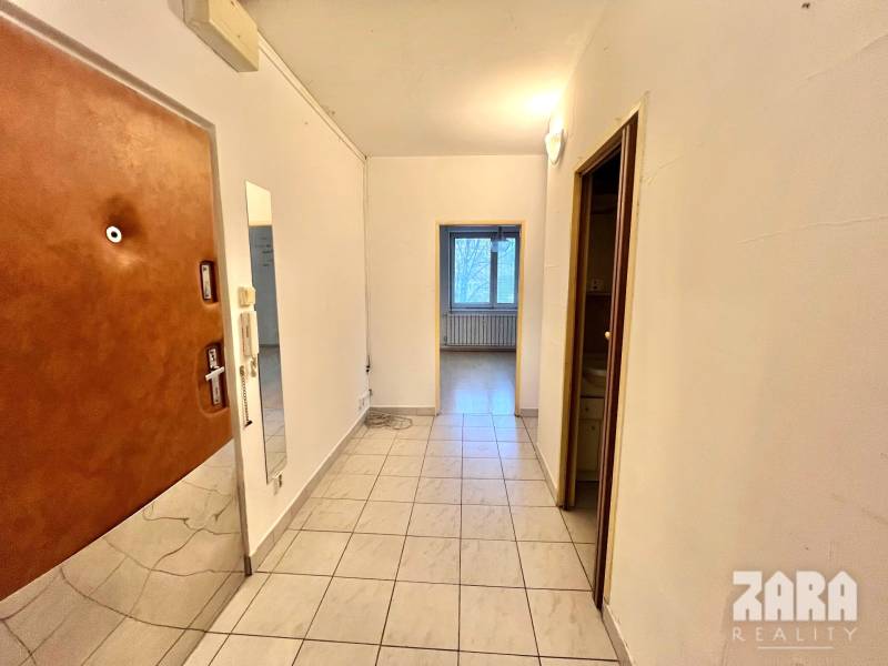 Flur in einer 3-Zimmer-Wohnung mit Fliesen und Eingangstür.