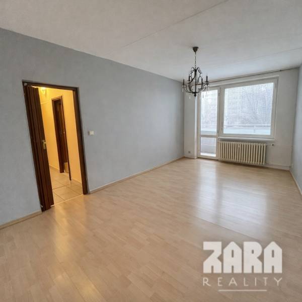 Ein Zimmer mit Holzboden und einem Kronleuchter in einer 3-Zimmer-Wohnung.