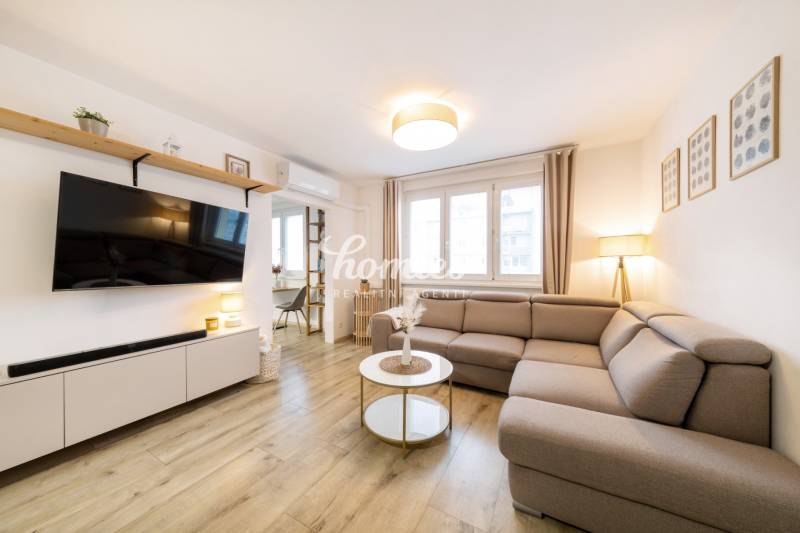 Wohnzimmer in einer 2-Zimmer-Wohnung mit einem bequemen Sofa und einem Holzboden.