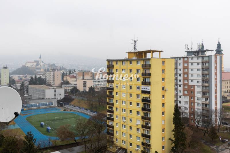 Blick auf Nitra von der Štúrová-Straße mit 3-Zimmer-Wohnungen, einem gelben Plattenbau und einem Sportplatz.