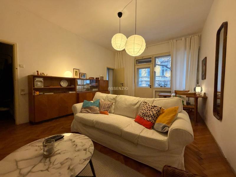 Wohnzimmer in einer Zweizimmerwohnung mit Holzboden und bequemer Couch.