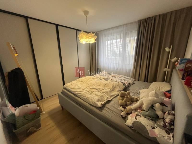 Schlafzimmer mit Bett, Einbauschrank, Vorhängen und Boden mit Holzdekor in einer 4-Zimmer-Wohnung.
