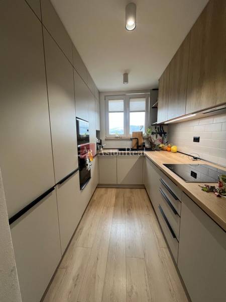 Küche in einer 4-Zimmer-Wohnung mit Holzboden, hellen Schränken, Fenster.