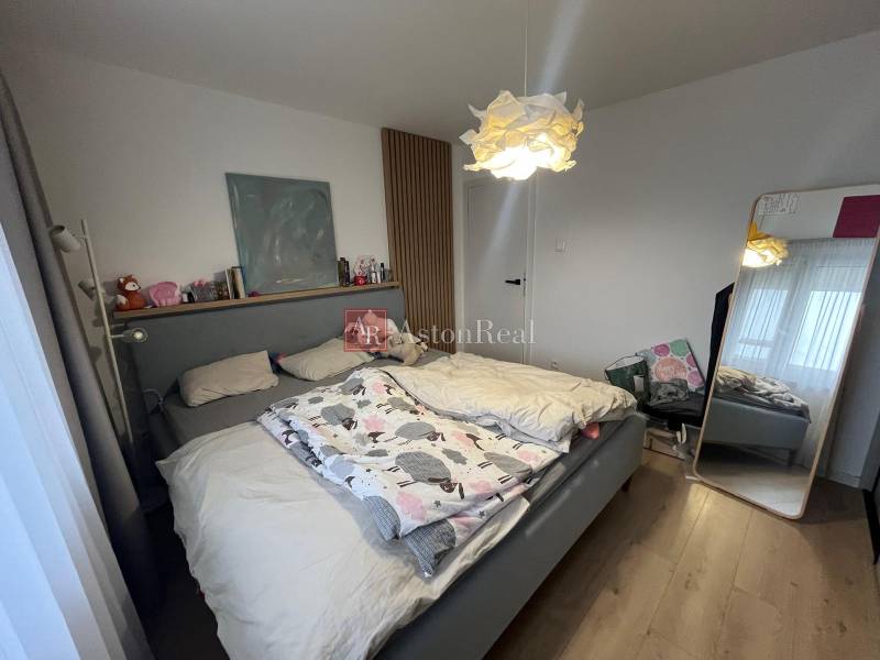 Schlafzimmer in einer 4-Zimmer-Wohnung mit einem komfortablen Bett und einem Boden mit Holzdekor.