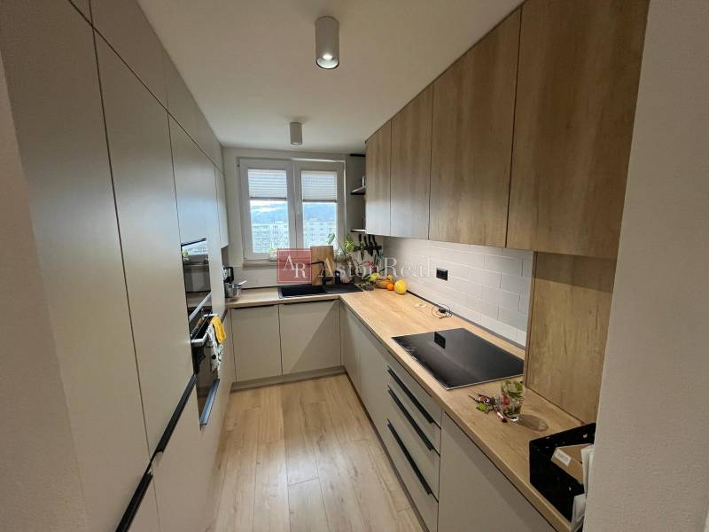 Küche in einer 4-Zimmer-Wohnung mit Küchenzeile, Geräten und Bodenbelag in Holzoptik.