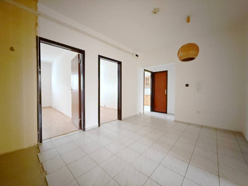 Innenraum einer 4-Zimmer-Wohnung mit weißen Wänden, Fliesen und einem Boden in Holzoptik.