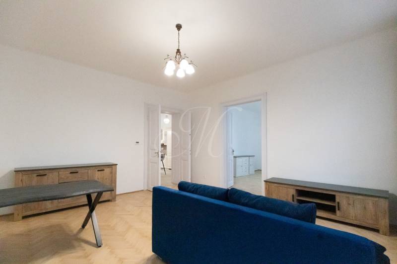 Wohnzimmer in einer 3-Zimmer-Wohnung mit Holzboden und einem blauen Sofa.