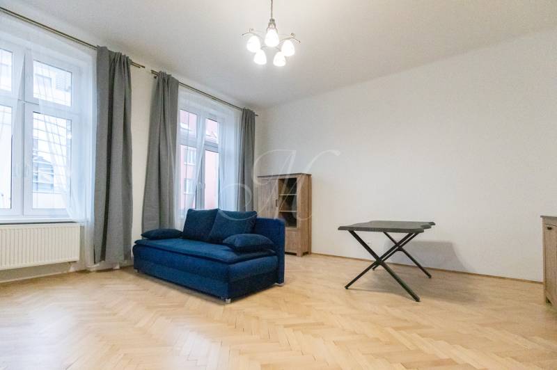 Wohnzimmer mit blauem Sofa und Holzboden in einer 3-Zimmer-Wohnung.