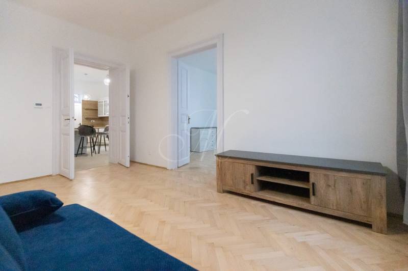 Wohnzimmer einer 3-Zimmer-Wohnung mit einem blauen Sofa und einem Boden in Holzoptik.