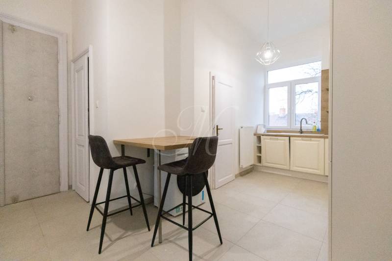 Küche in einer 3-Zimmer-Wohnung mit Bartresen, zwei Stühlen und einem großen Fenster.