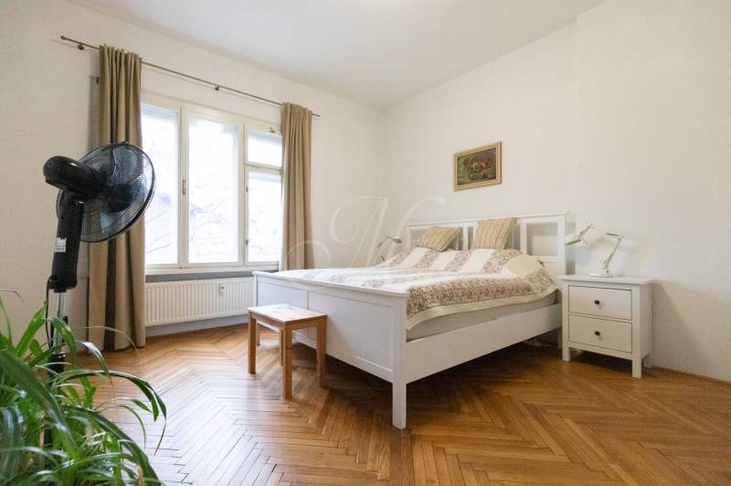 Schlafzimmer mit hellen Möbeln, großem Fenster und Boden mit Holzdekor in einer 2-Zimmer-Wohnung.