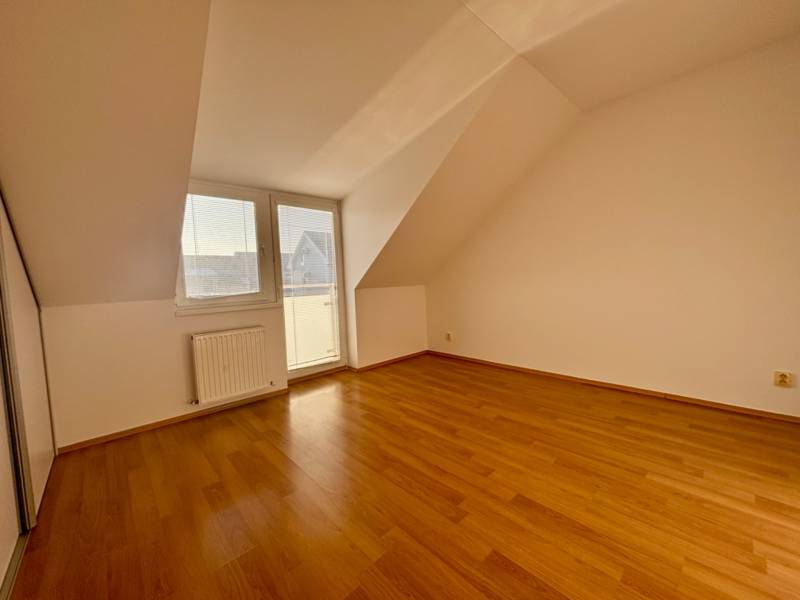 Ein Zimmer in einer 2-Zimmer-Wohnung mit Holzboden und Zugang zum Balkon.