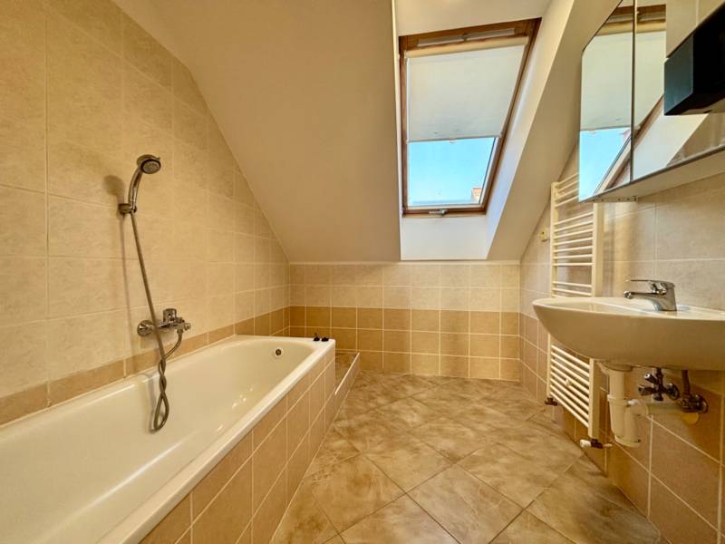 Badezimmer in einer 2-Zimmer-Wohnung mit Badewanne und Dachfenster.