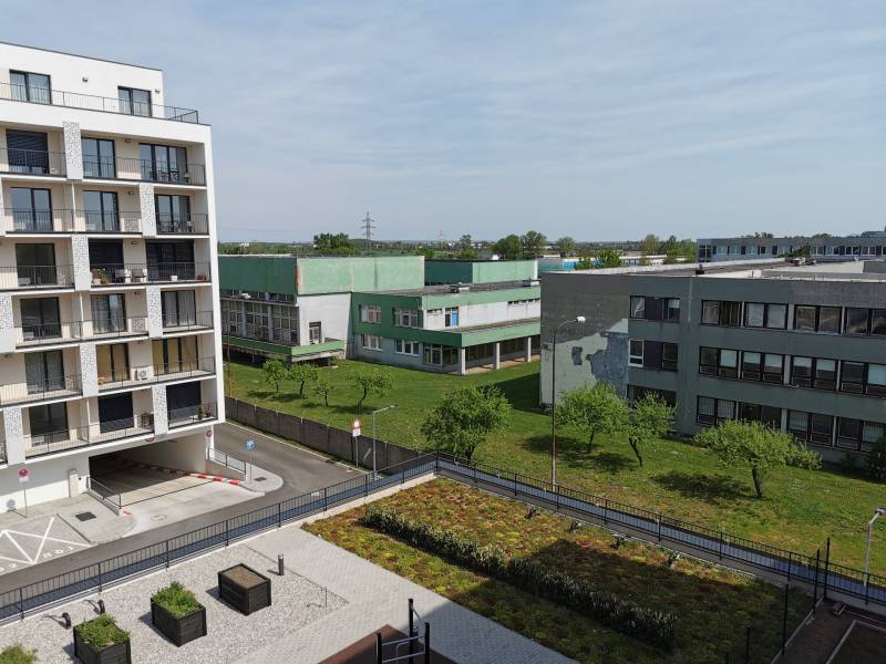 Blick auf Wohngebäude und Grünflächen in Eduard Wenzl in Bratislava-Rača, Garagen rechts.