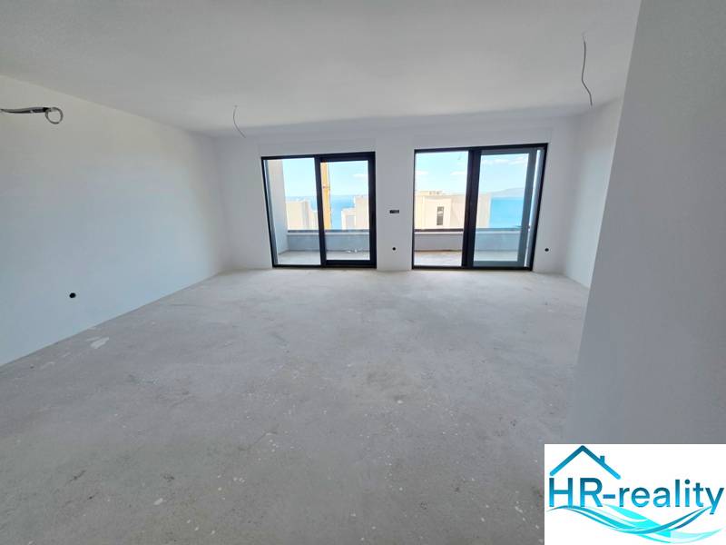 Innenraum einer Ferienwohnung mit Blick durch große Fenster auf das Meer.