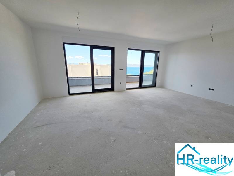 Ein heller Raum in einer Ferienwohnung mit großen Fenstern und Blick auf das Meer.