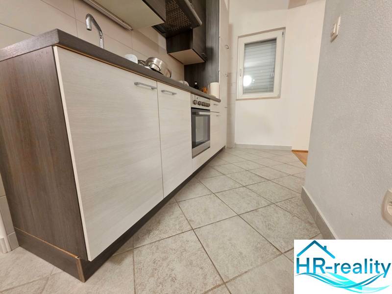 Küche in einer Ferienwohnung mit Fliesenboden und einer modernen Küchenzeile mit dunklen Schränken.