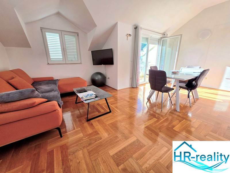 Ferienwohnung mit orangefarbenem Sofa, Esstisch und Holzboden.