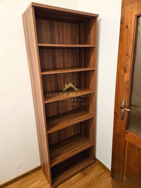 Ein Regal mit fünf Regalböden neben einer Holztür und einem Boden mit Holzdekor.