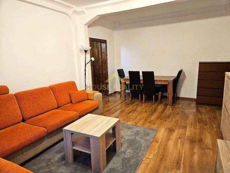 3-Zimmer-Wohnung mit einem orangefarbenen Sofa, einem Holztisch und einem Boden mit Holzdekor.